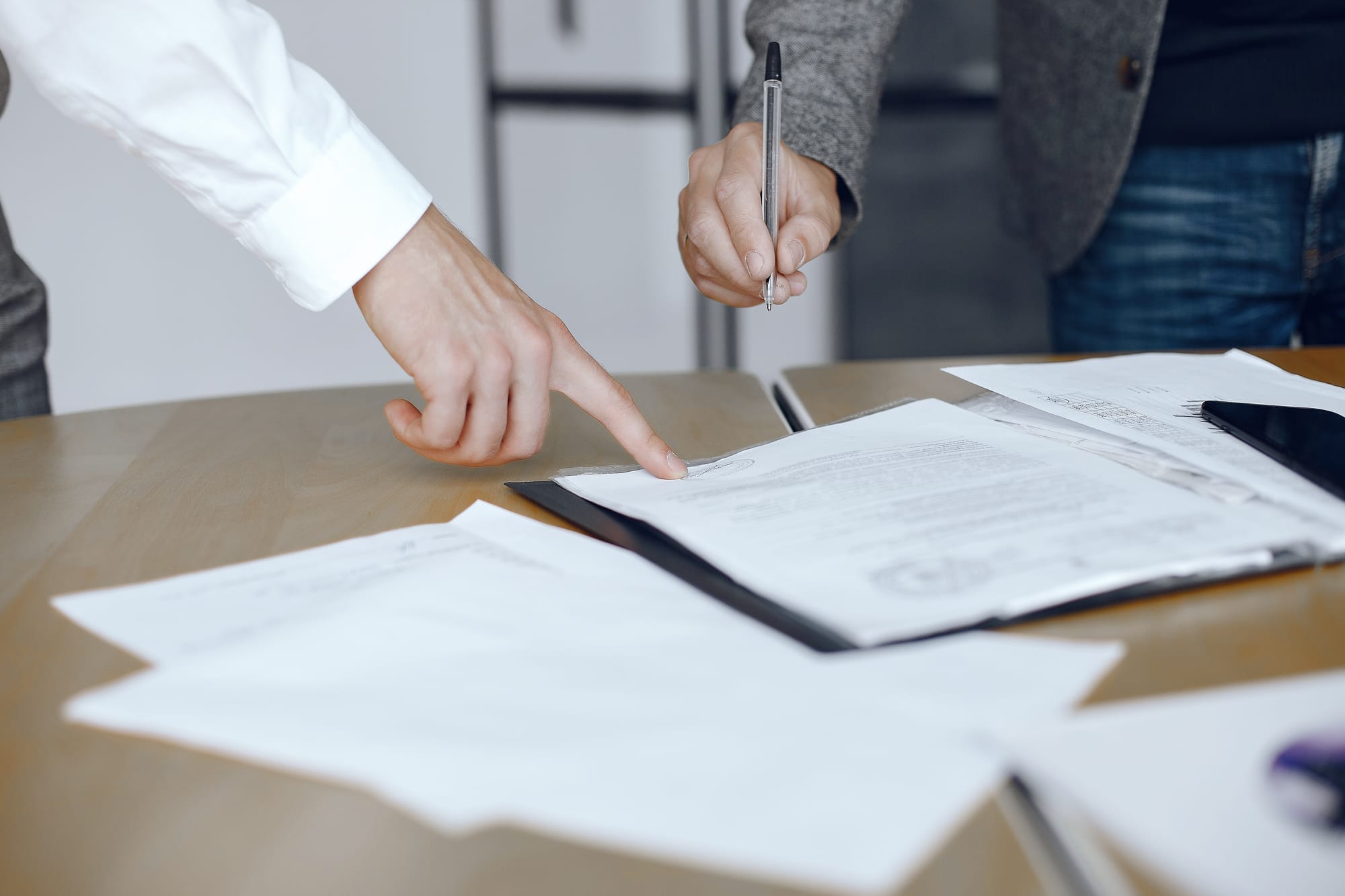 Empresários reunidos ao redor da mesa, assinando um documento.